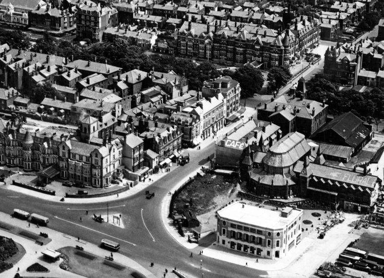 An aerial view of Coronation Walk in 1930 shows the Winter Gardens complex being gradually dismantled on the right. The Pavilion had already been replaced by the Empire Theatre, whose curved roof is attempting to echo the original. On Coronation Walk itself, the 1920s Pavilion Hotel (The Phoenix in 2022) is setting a trend for bright modernity. Soon afterwards, the small two storey Crown Hotel will be raised and re-fronted.